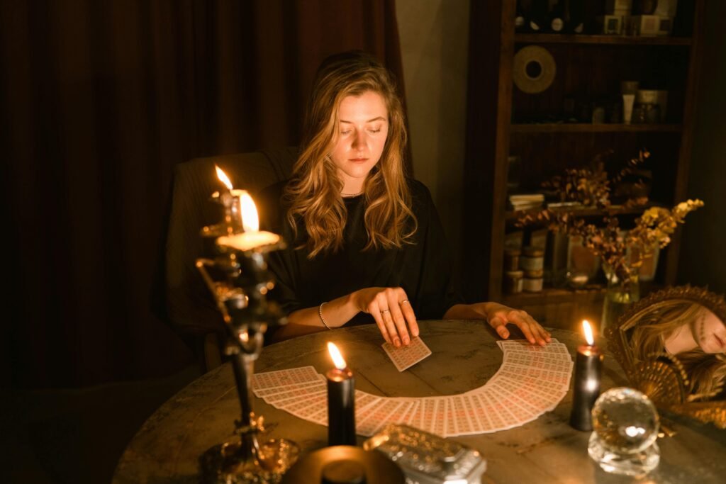 A woman sitting in a dimly lit room, reading tarot cards by candlelight.